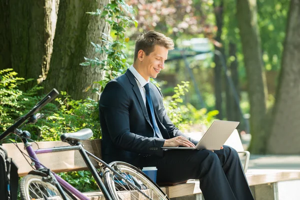 Homme d'affaires assis sur le banc en utilisant un ordinateur portable — Photo