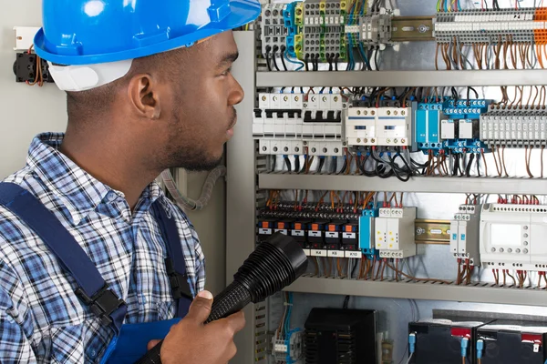 Technicien analysant Fusebox avec lampe de poche — Photo