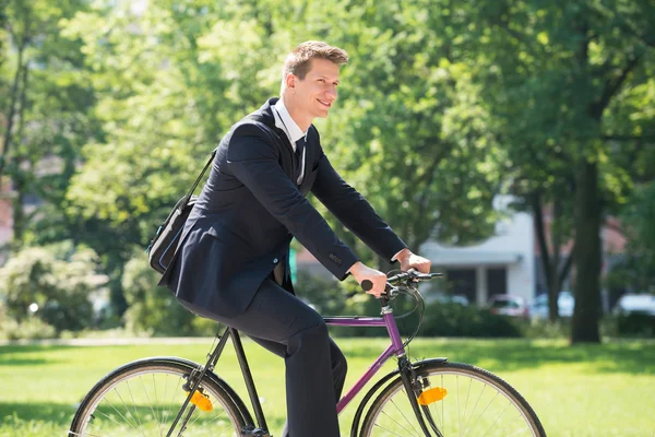 Бизнесмен катается на велосипеде в парке — стоковое фото