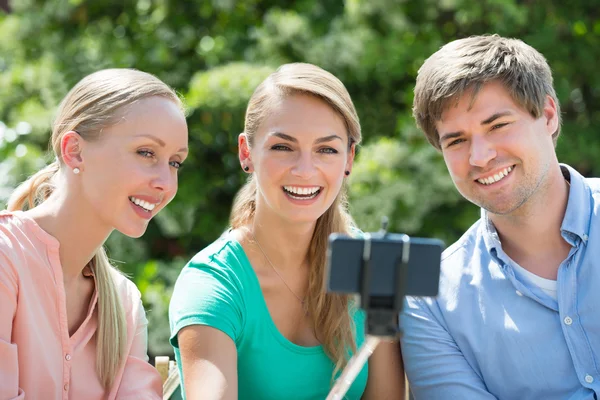 Amigos felizes tomando selfie com vara de selfie — Fotografia de Stock