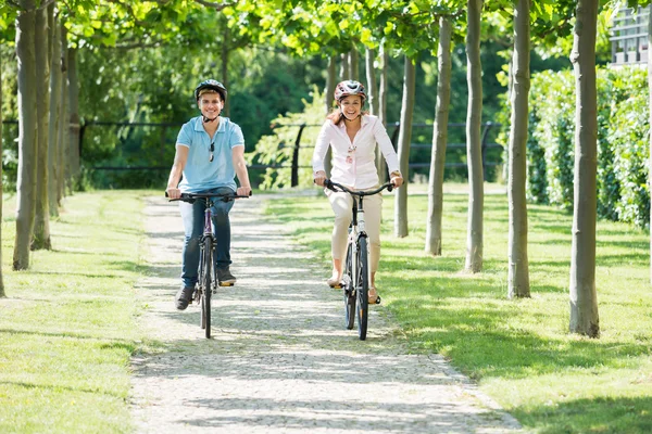 Feliz jovem casal de bicicleta no parque — Fotografia de Stock