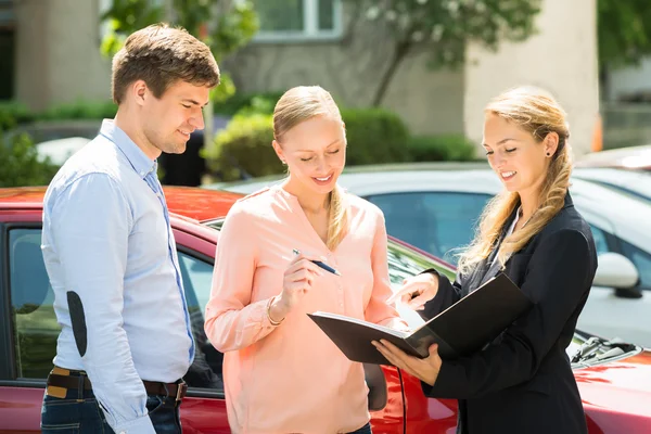 Verkoopster Contract papier uit te leggen aan paar — Stockfoto