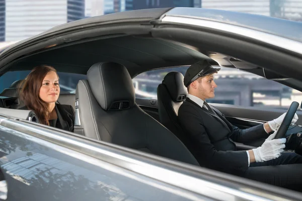 Junge Frau fährt mit Chauffeur im Auto — Stockfoto