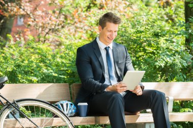 Dijital Tablet kullanarak bankta oturan işadamı