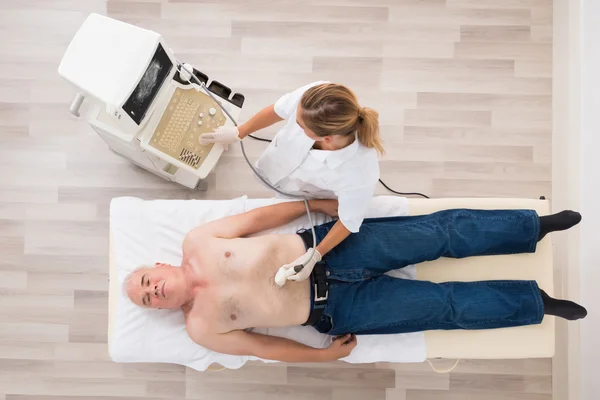 Médico que usa ultrasonido en el abdomen de un paciente masculino mayor —  Fotos de Stock