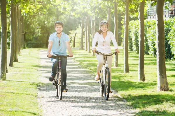 幸せな若いカップル公園で自転車に乗ること — ストック写真