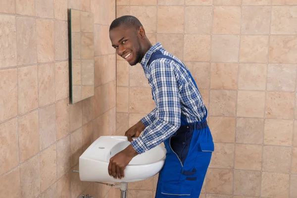 Encanador masculino fixando o dissipador no banheiro — Fotografia de Stock