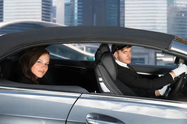 Mujer joven montando en un coche con chófer — Foto de Stock