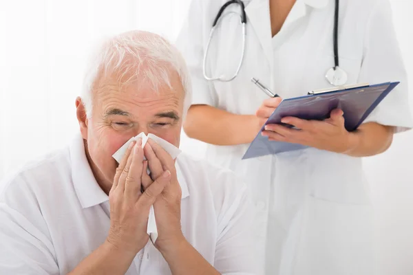 Uomo anziano infettato da freddo soffiando il naso in clinica — Foto Stock