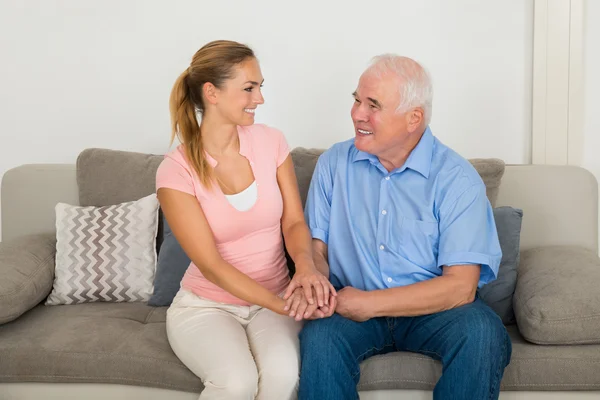 Frau sitzt auf Sofa und hält die Hand ihres Vaters — Stockfoto