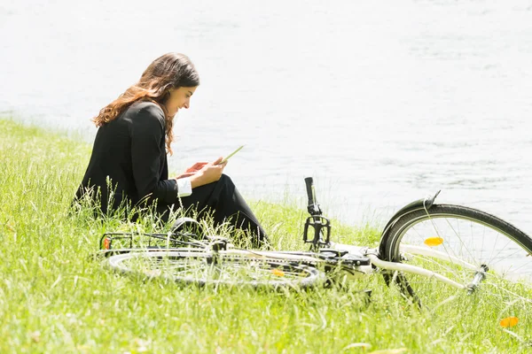 Empresária sentada na grama usando tablet digital — Fotografia de Stock