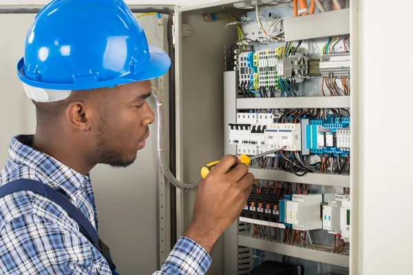 Electricista examinando caja de fusibles con destornillador — Foto de Stock