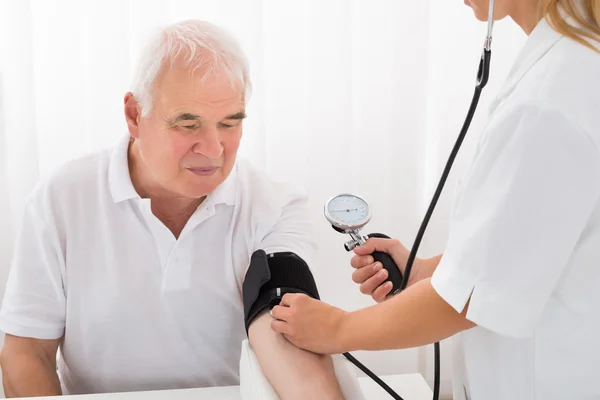 Женщина-врач проверяет кровяное давление у пациента мужского пола — стоковое фото