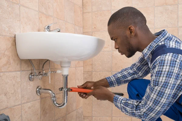 Plomero fregadero de reparación en el baño — Foto de Stock