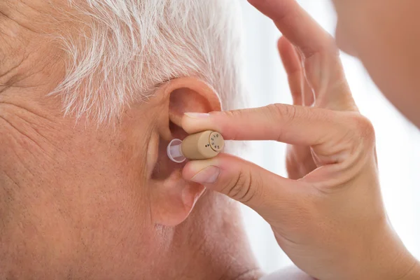 Doktor uvedení naslouchátko pacienta do ucha — Stock fotografie