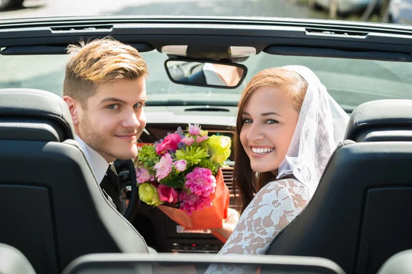 Μόλις παντρεμένο ζευγάρι με ανθοδέσμη στο αυτοκίνητο — Φωτογραφία Αρχείου