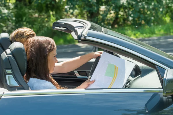 Frau schaut auf Landkarte, während Mann Auto fährt — Stockfoto