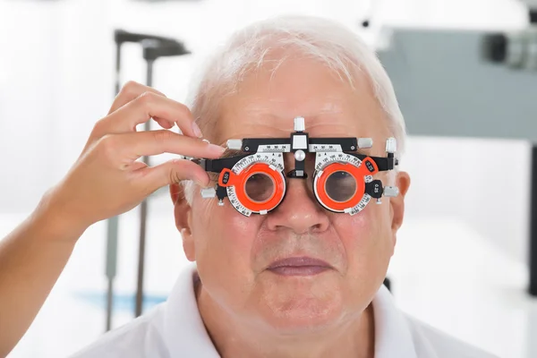 Um Optometrist que verifica a visão do paciente com quadro experimental — Fotografia de Stock