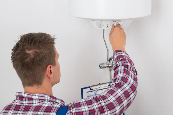 Plomero masculino que ajusta la temperatura de la caldera eléctrica —  Fotos de Stock