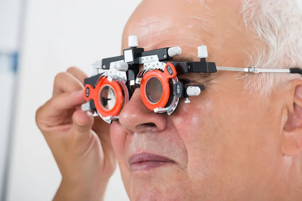Um Optometrist que verifica a visão do paciente com quadro experimental — Fotografia de Stock