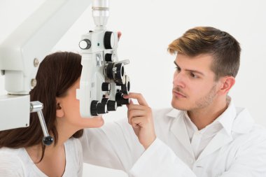 Male Ophthalmologist Examining Female Patient Eyes clipart