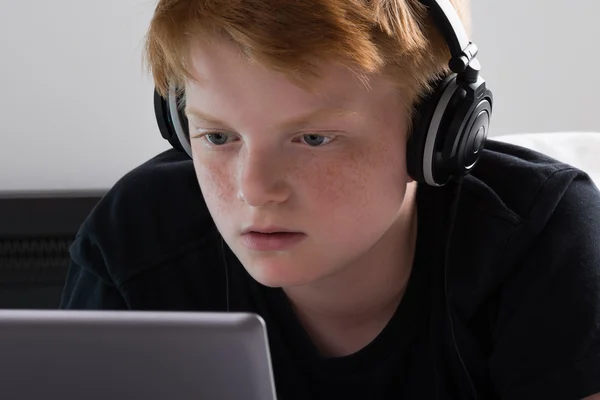 Niño escuchando música en el ordenador portátil —  Fotos de Stock