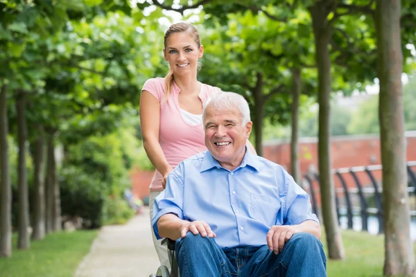 Frau mit ihrem alten Vater im Rollstuhl — Stockfoto