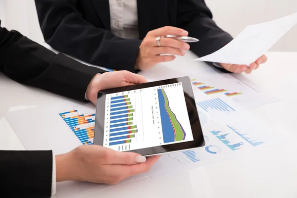 Geschäftsleute vergleichen Grafiken auf digitalem Tablet — Stockfoto