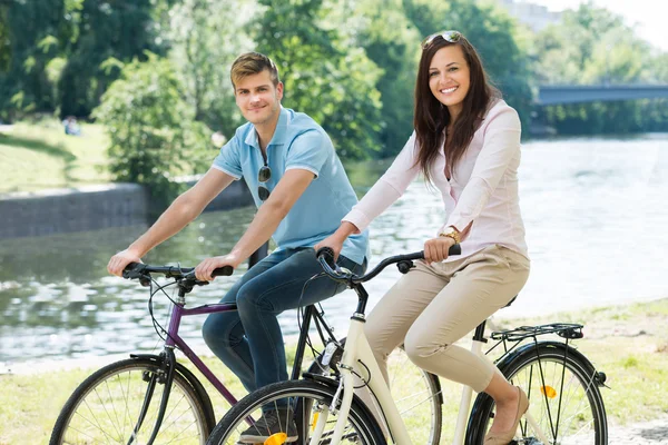 คู่รักยิ้มบนจักรยานในสวนสาธารณะ — ภาพถ่ายสต็อก