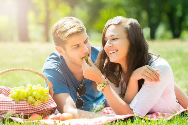Sorrindo mulher alimentando uva para seu namorado — Fotografia de Stock