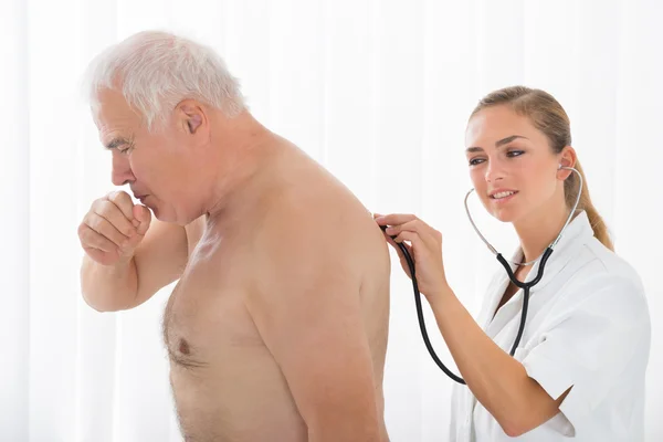 Arts met behulp van de stethoscoop op patiënt achterkant — Stockfoto