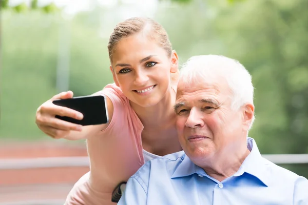 Žena s její otec pořizování Selfie na mobilním telefonu — Stock fotografie