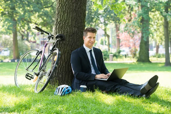 Homem de negócios usando laptop no parque — Fotografia de Stock