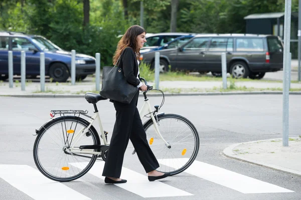 Uśmiecha się kobieta z torebka dojazdów do pracy na rowerze — Zdjęcie stockowe