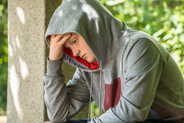 Unglücklicher Junge sitzt im Park — Stockfoto