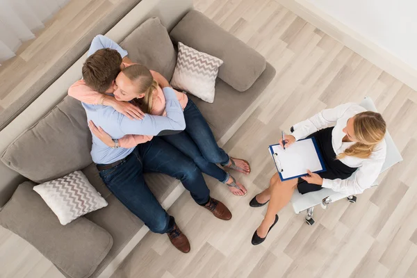 Paar sitzt auf Sofa und umarmt sich vor Psychologen — Stockfoto