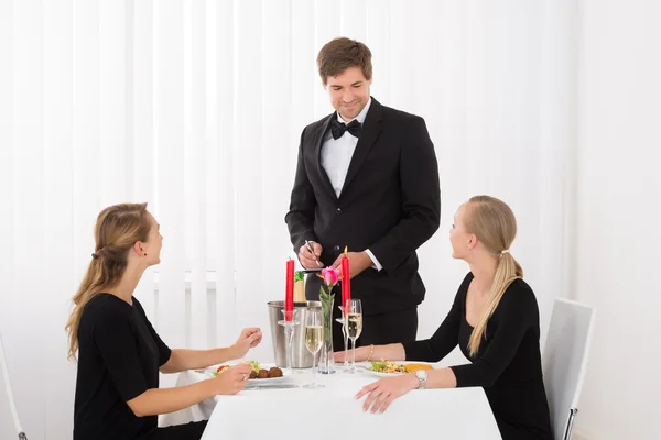 Kellnerin nimmt Bestellung von Freundinnen entgegen — Stockfoto