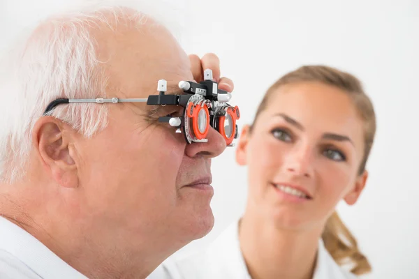 Ein Augenarzt überprüft das Sehvermögen des Patienten mit Versuchsrahmen — Stockfoto