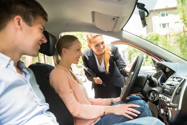 Verkäuferin zeigt Paar Auto — Stockfoto