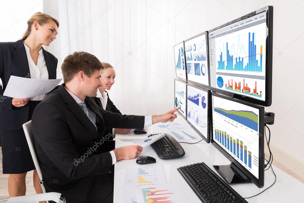 Businesspeople Analyzing Graphs On Multiple Computers