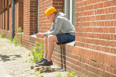 Çocuk kaykay cep telefonunu kullanma