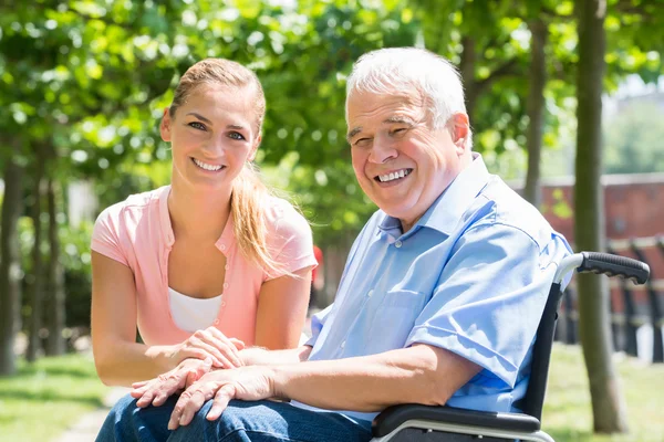 Mujer joven sonriente con su padre discapacitado — Foto de Stock