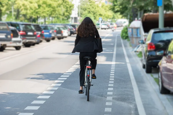 Jeune femme d'affaires à vélo sur la rue — Photo