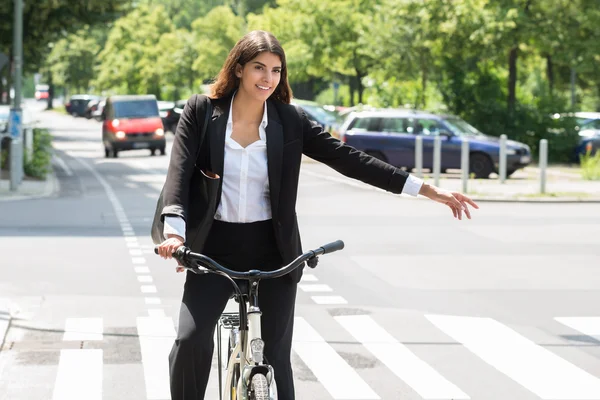 Junge Geschäftsfrau zeigt Kurve auf dem Fahrrad — Stockfoto