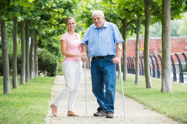 Mulher com seu pai deficiente em pé no parque — Fotografia de Stock