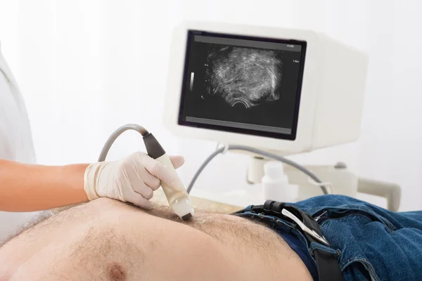 Main du médecin avec échographie sur l'abdomen du patient masculin — Photo