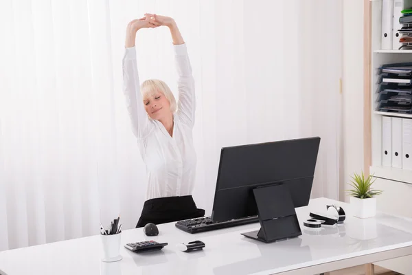 Empresaria estirándose en la oficina — Foto de Stock