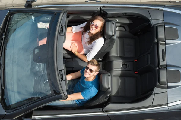 Glückliches junges Paar sitzt im Auto — Stockfoto