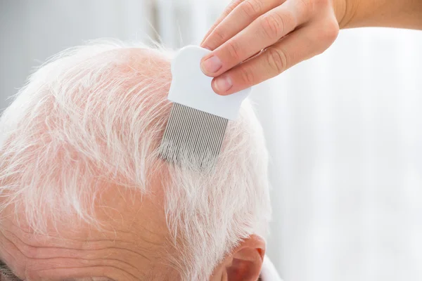 Medico che fa il trattamento sui capelli del paziente con pettine — Foto Stock