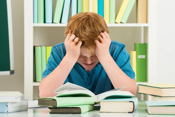 Уставший мальчик учится в библиотеке — стоковое фото